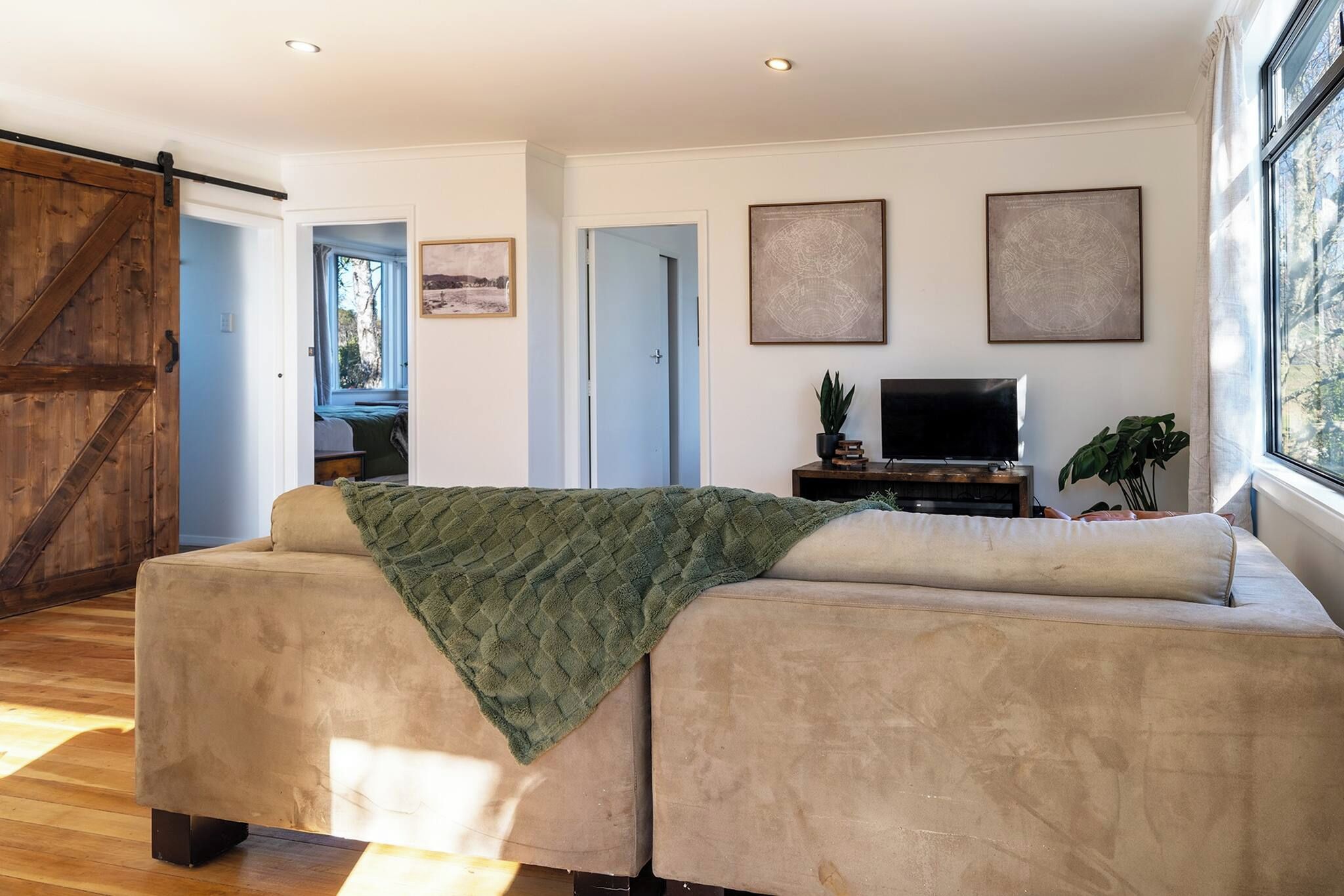 A modern living room with a large sofa, a flat-screen TV, and a sliding barn door.