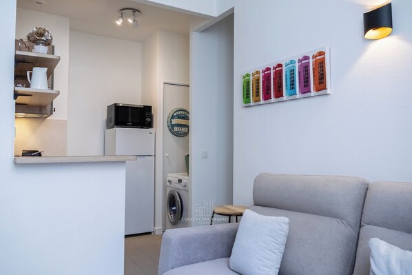 Una cucina moderna con forno a microonde, lavatrice e un piccolo tavolo.