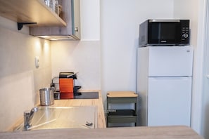 Una cucina compatta con forno a microonde, frigorifero e un lavandino.