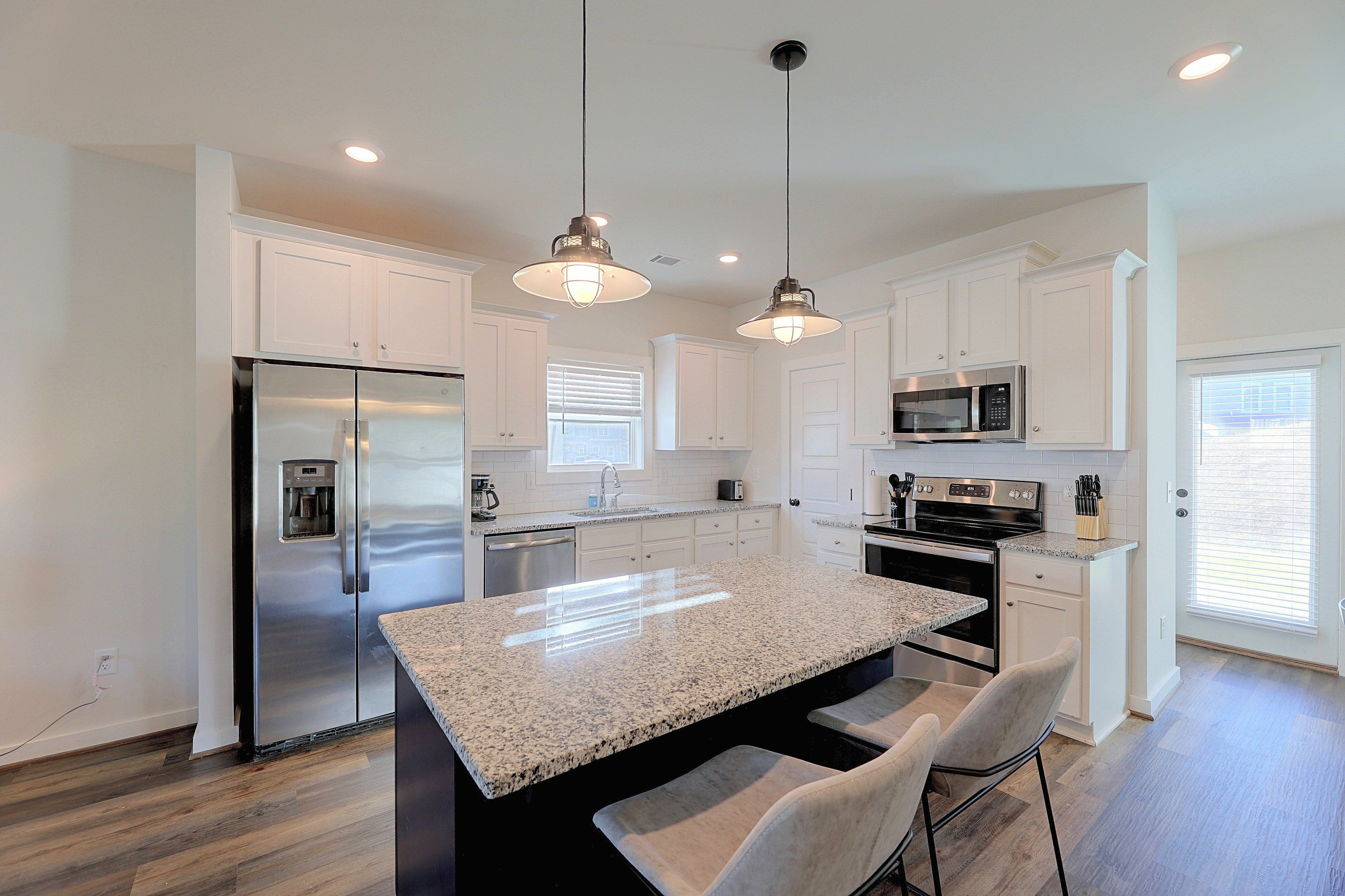 A modern kitchen with stainless steel appliances, granite countertops, and pendant lighting.