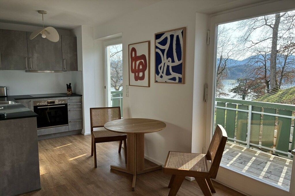 Une cuisine moderne avec un coin repas, une vue sur un lac et des œuvres d’art accrochées au mur.