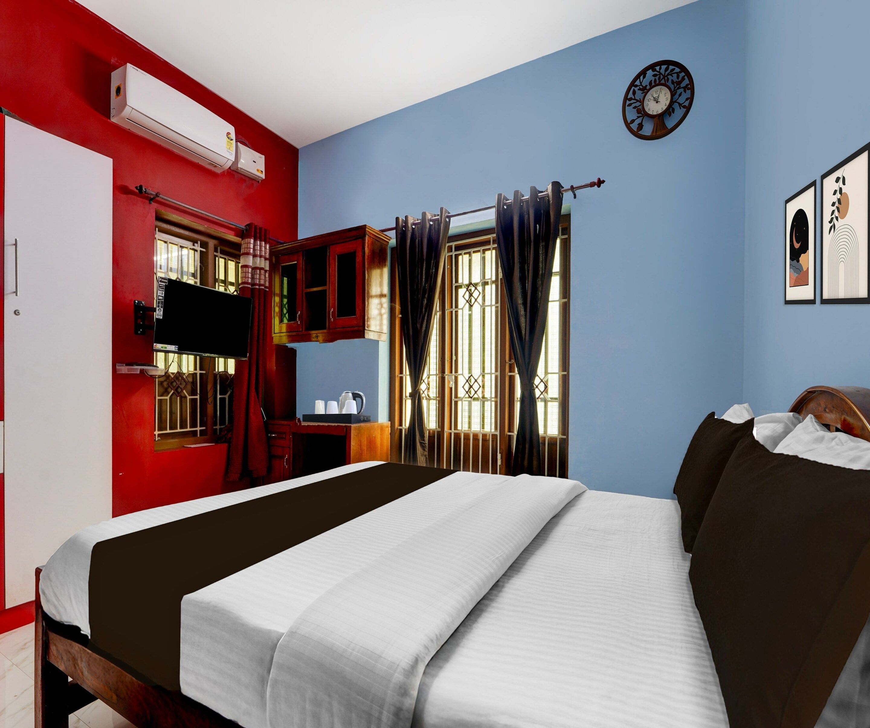 A hotel room with a bed, a TV, a window with curtains, and a wall clock.