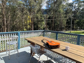 Una terrazza esterna con tavolo e sedie di legno, e una chitarra.
