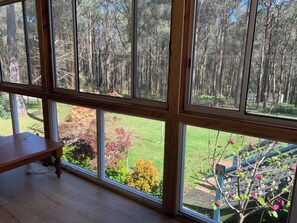 A room with large windows offering a view of a forest and a garden. - Forest cottage Bed-n-Breakfast (Reefton)
