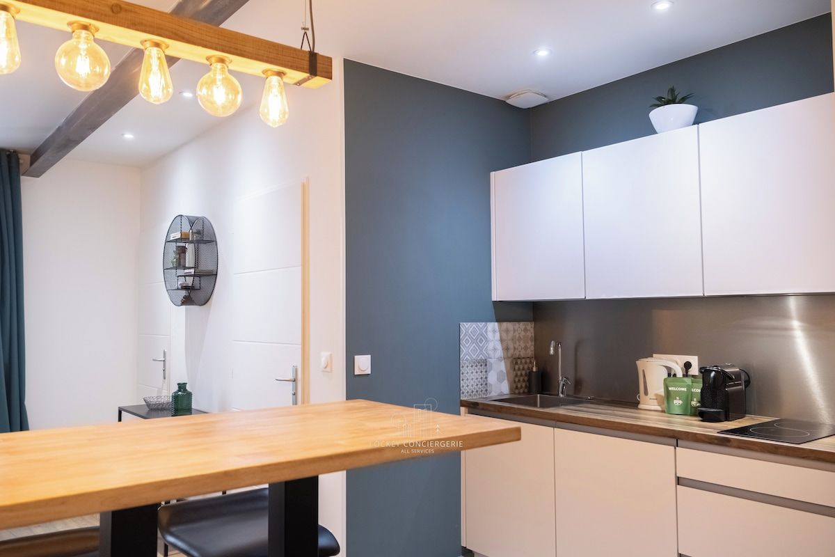 Una cocina moderna con armarios blancos, encimera de madera y una lámpara colgante.