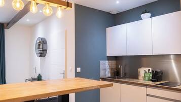 Una cocina moderna con armarios blancos, encimera de madera y una lámpara colgante.