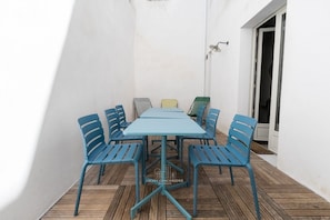 A patio with a table and chairs, a door, and a wall-mounted light fixture. - Large Apartment with Patio - Steps from the Harbor (La Rochelle)