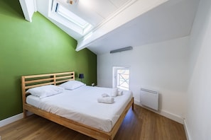 Una camera da letto con un letto in legno, un comodino, una lampada, un termosifone e un lucernario.