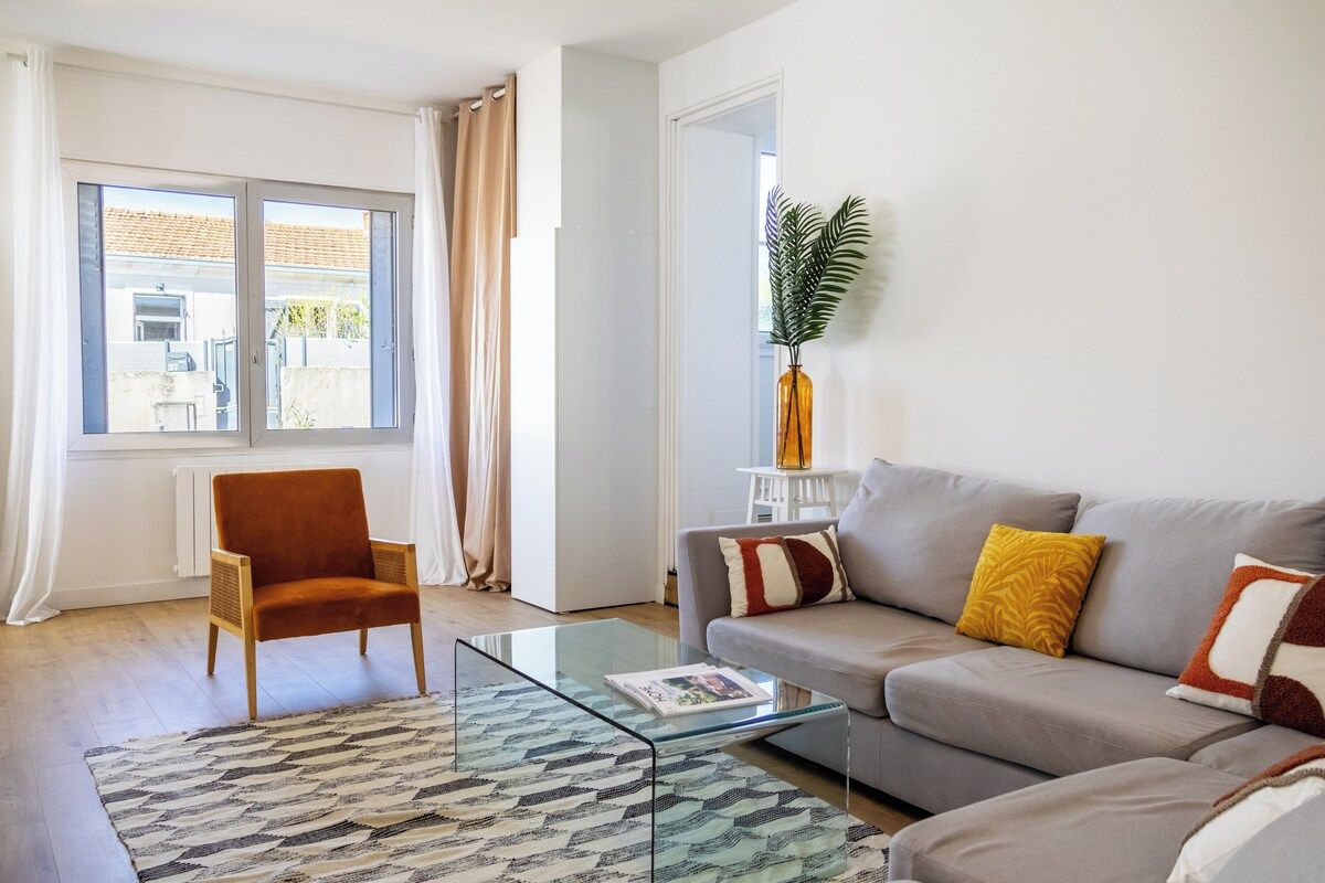 A living room with a sofa, armchair, glass coffee table, and patterned rug.