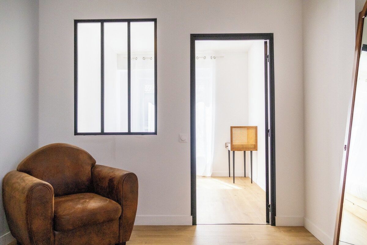 A room with a brown leather chair, a window with blinds, and a door leading to another room.