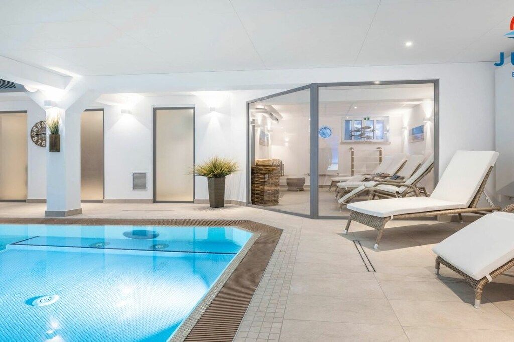 A swimming pool area with lounge chairs and a glass partition.