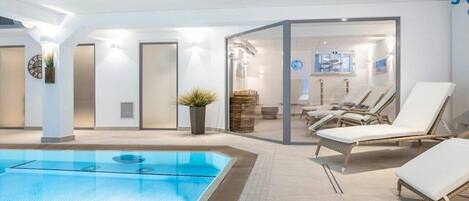 A swimming pool area with lounge chairs and a glass partition.