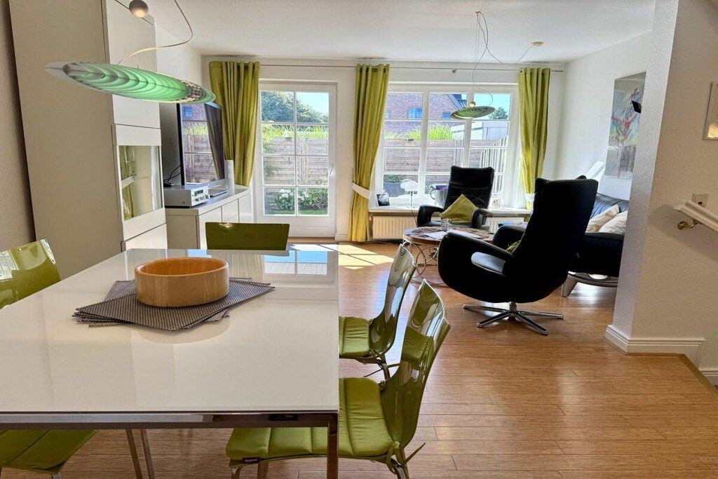 A modern kitchen with a dining area, a black chair, and a table with a bowl.