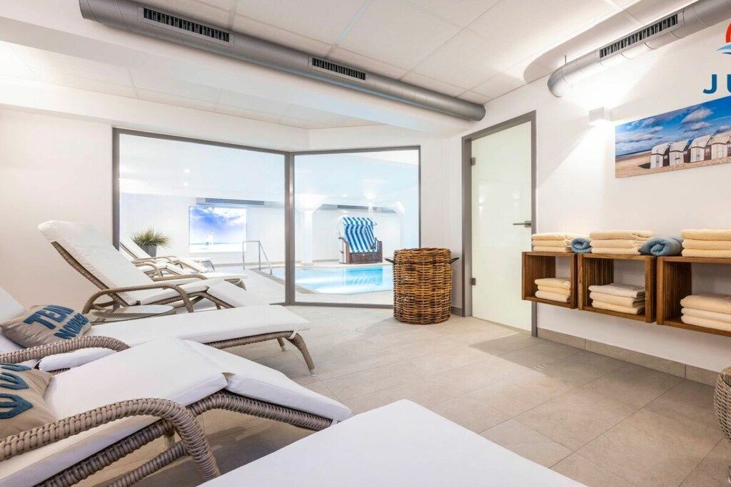 A spa room with lounge chairs, a small pool, and a wall with towels.