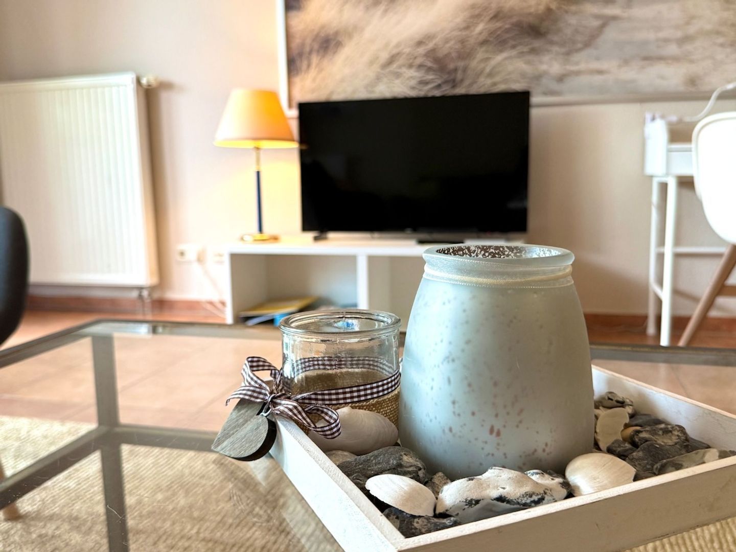 A cozy living room with a television, a lamp, and a decorative tray with a jar and stones.