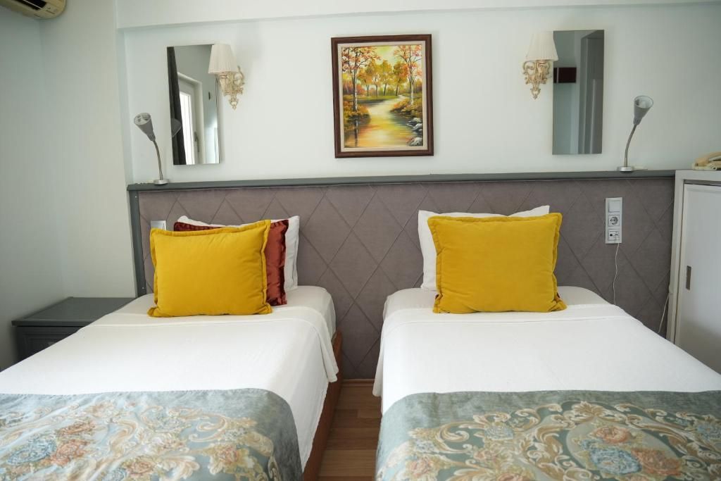 A hotel room with two beds, a painting on the wall, and a mirror above the beds.