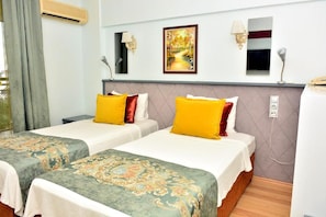 Quarto de hotel com duas camas, um quadro na parede e um abajur.