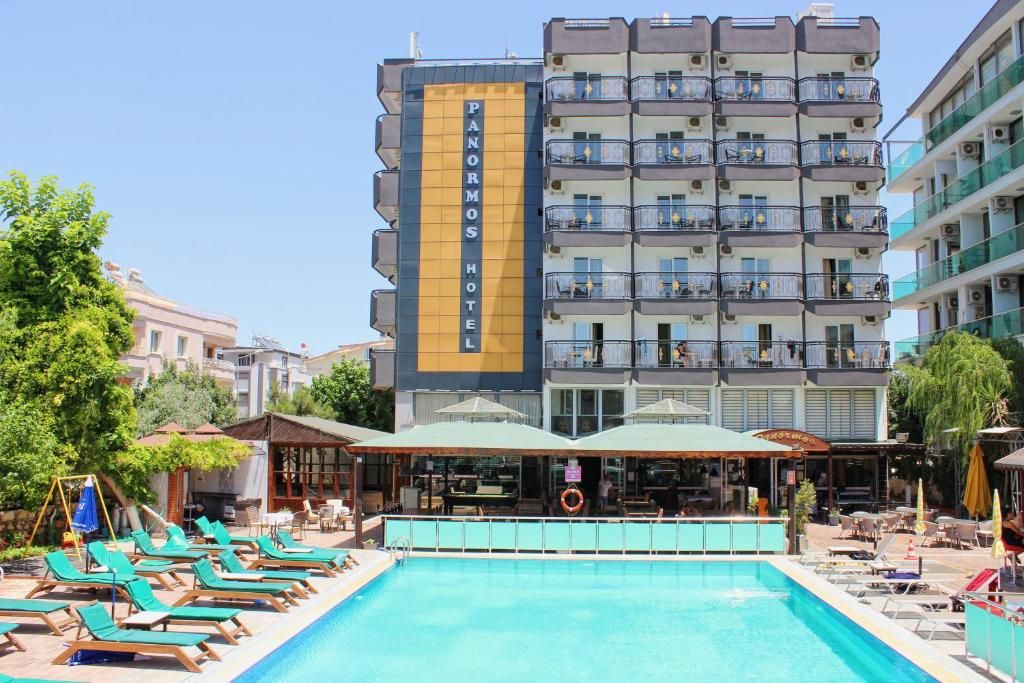 Un hotel con piscina, varios balcones y zonas de estar al aire libre.