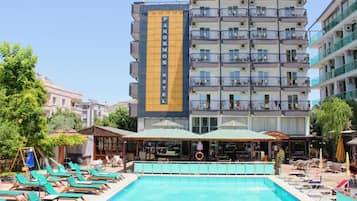 Un hotel con piscina, varios balcones y zonas de estar al aire libre.
