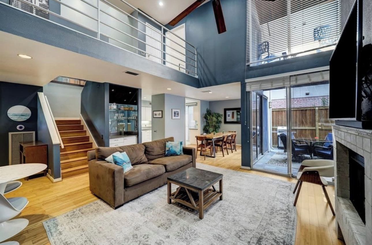 A spacious living area with a staircase, a fireplace, and a dining area.