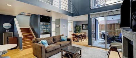 A spacious living area with a staircase, a fireplace, and a dining area.