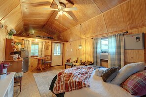 Un interior de cabaña acogedor con una cama, una mesa de comedor y una zona de cocina.