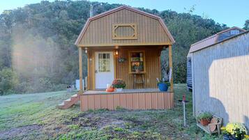 A wooden cabin with a porch, a door, and a window.
