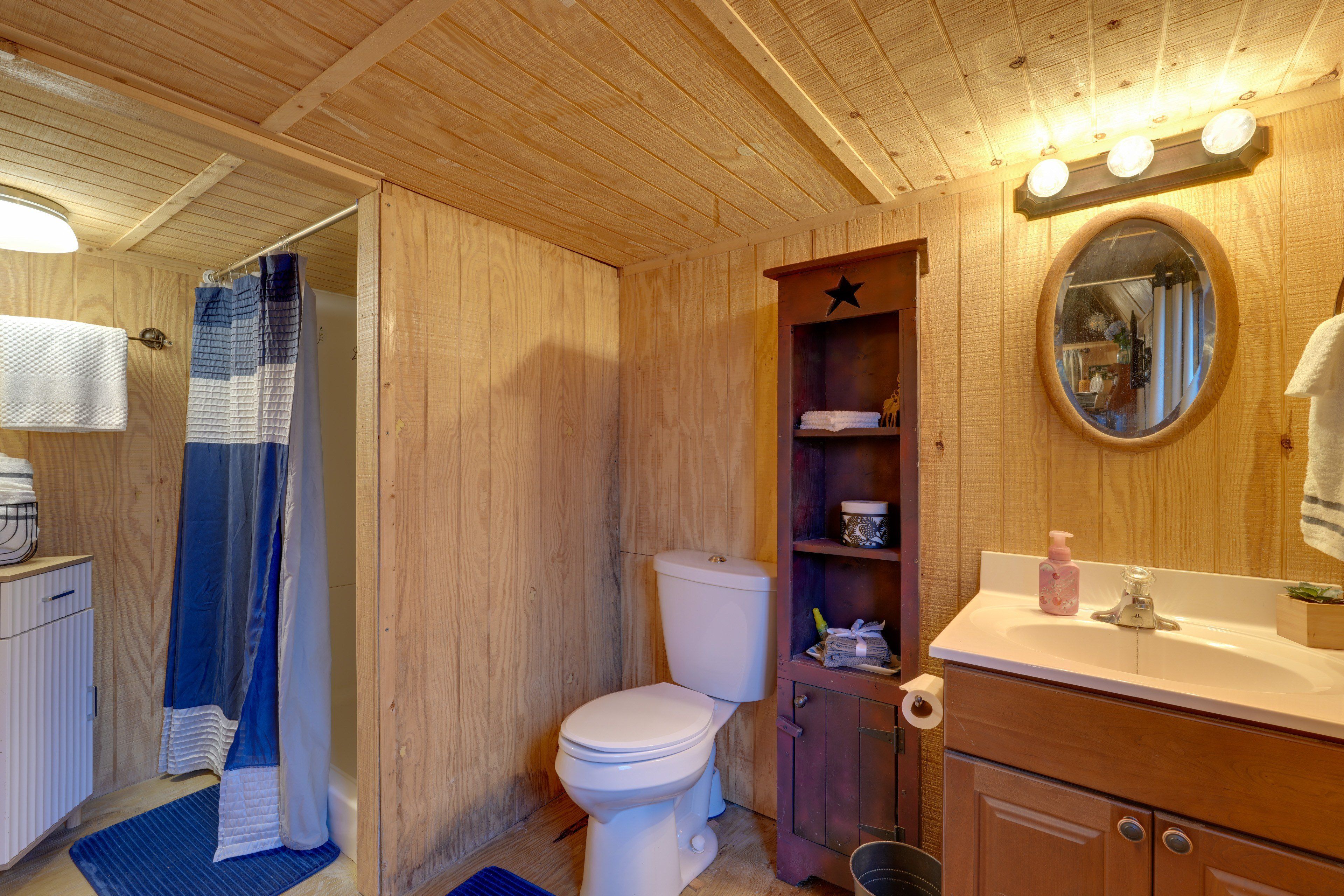 Een houten badkamer met toilet, wastafel en spiegel.
