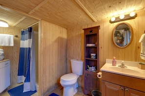 A wooden bathroom with a toilet, a sink, and a mirror.