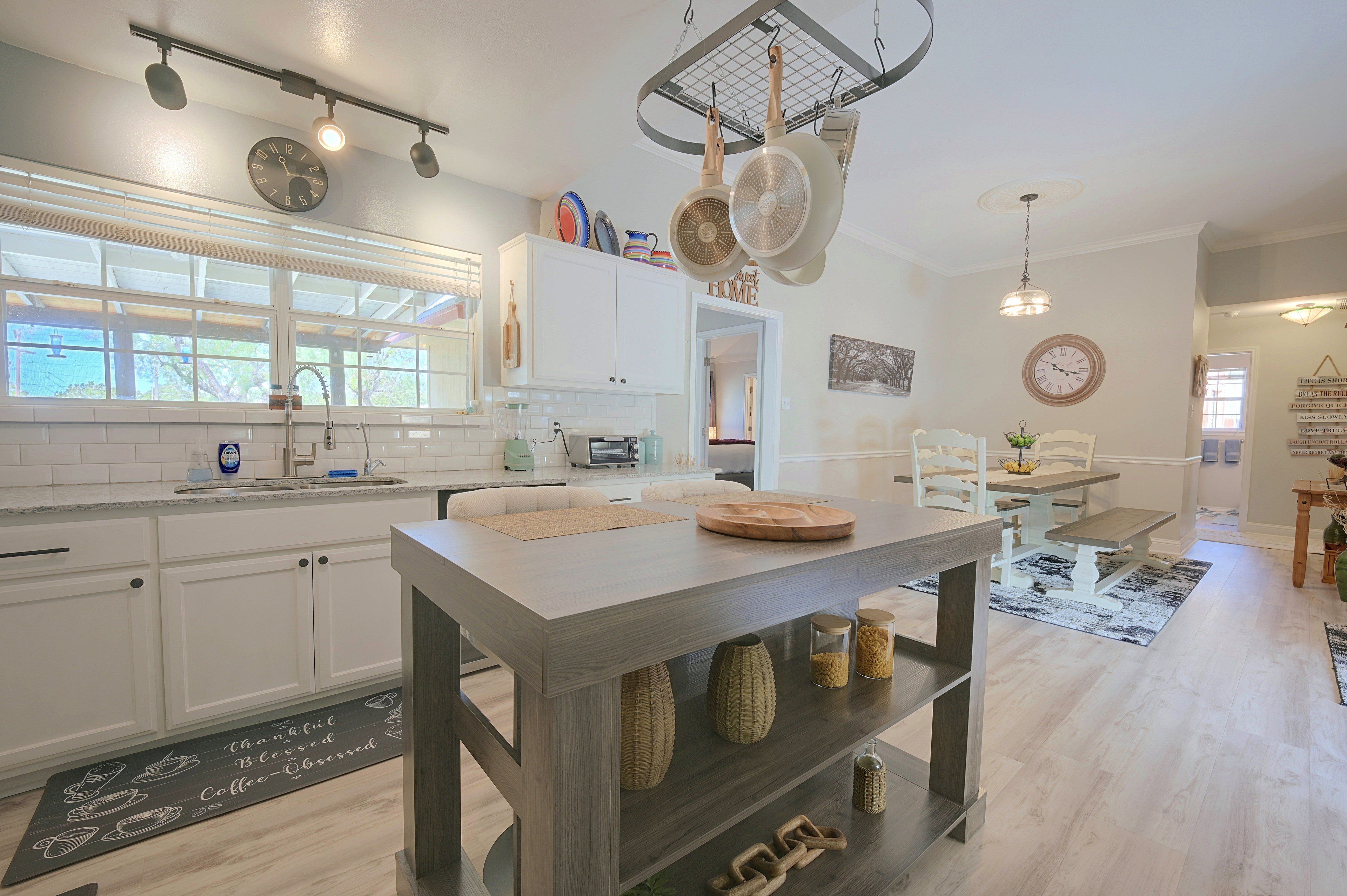 A modern kitchen with white cabinetry, a central island, and a dining area with a table and chairs.