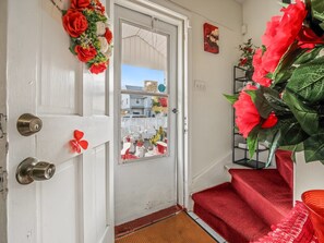 A white door with a red flower arrangement, a red carpeted staircase, and a red chair. - Cozy private room with private bathroom in a home where the owners live (Bridgeport)