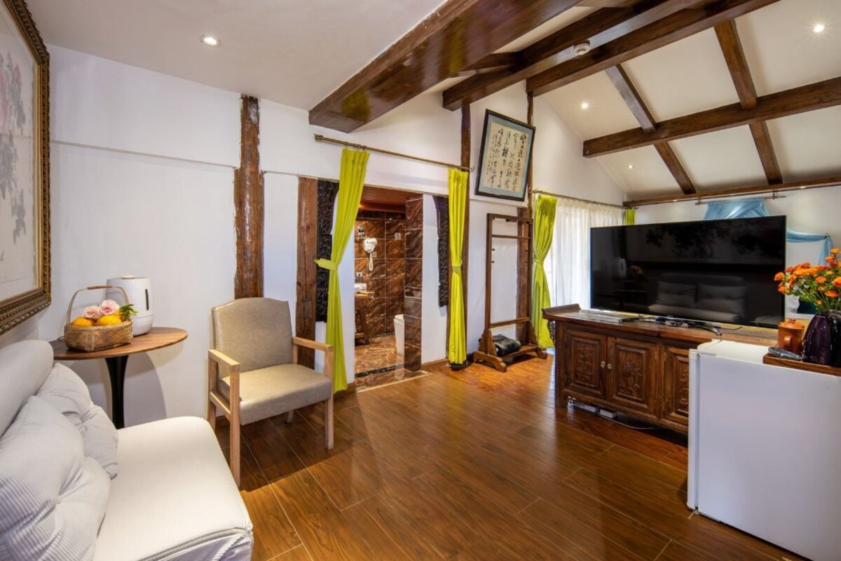 A living room with a sofa, a television, a cabinet, and a dining area with a table and chairs.