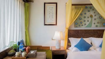 A hotel room with a bed, bedside table, lamp, and a wall with a framed picture.