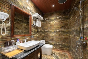 A bathroom with a marble wall, a sink, a toilet, and a shower. - Oriental Garden Tea Lodge,Lijiang (Lijiang)