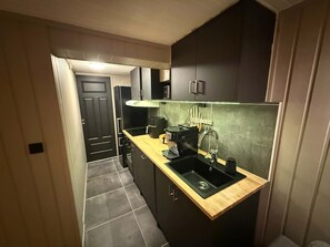 Una cocina compacta con cubierta de madera, un lavamanos negro y armarios oscuros.