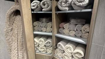 A wooden cabinet with multiple shelves holding rolled towels.