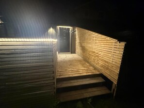 Una escalera conduce a una puerta con celosía metálica, rodeada de paneles de madera.
