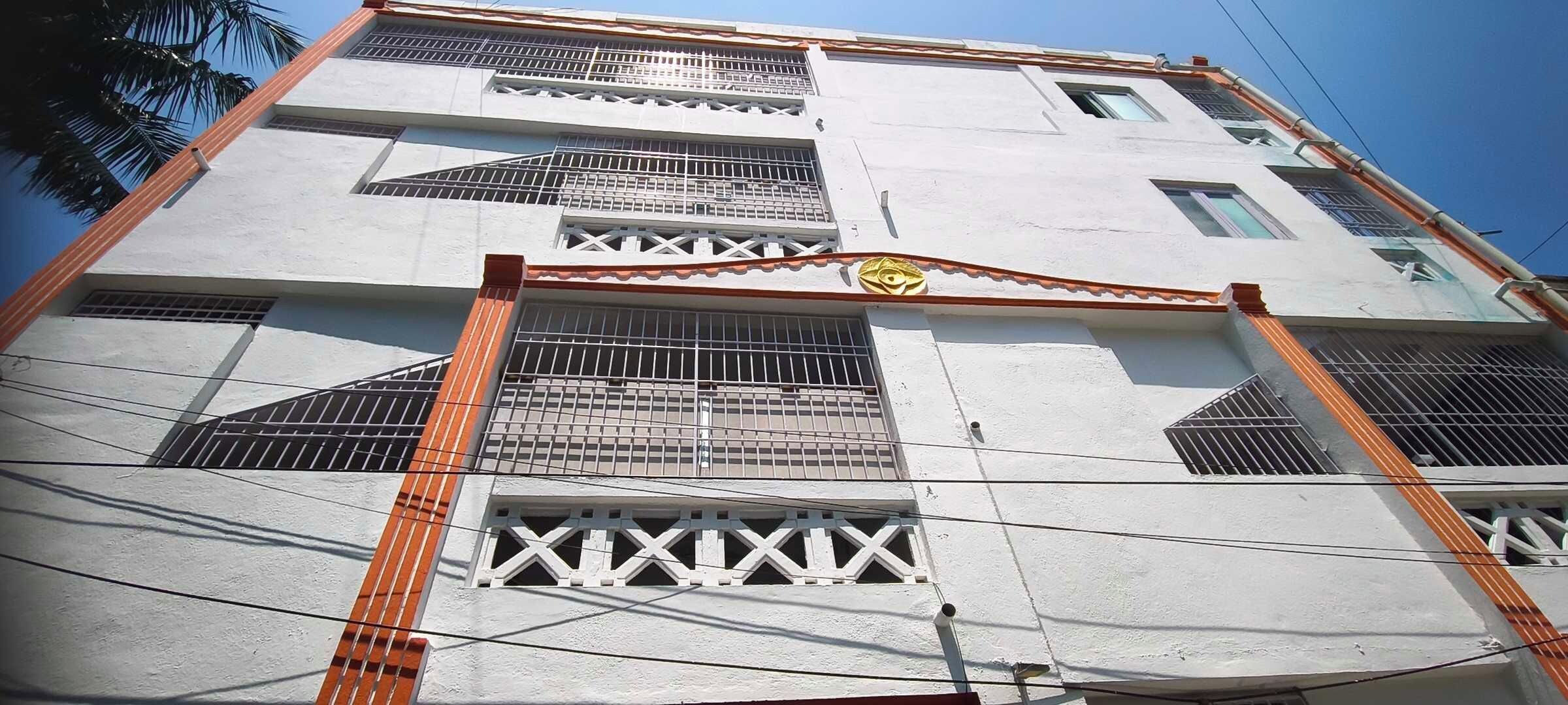Un edificio de varios pisos con ventanas protegidas por rejas y un portón de acceso central.