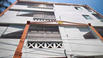 Un edificio de varios pisos con ventanas protegidas por rejas y un portón de acceso central.