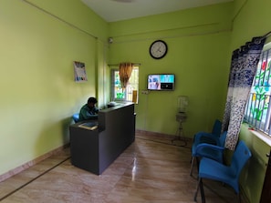 A reception area with a desk, chairs, a clock, a television, and a water dispenser. - Hotel O VKS Palace (Chennai)