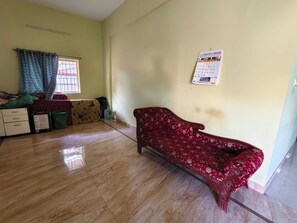 A room with a sofa, a bed, a window with curtains, a calendar on the wall, and a water dispenser. - Hotel O VKS Palace (Chennai)