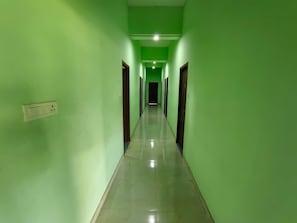 A corridor with green walls and a tiled floor, leading to a door at the end. - Hotel O VKS Palace (Chennai)