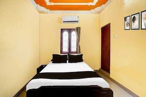 A hotel room with a bed, air conditioning unit, window with curtains, and framed artwork on the wall. - Hotel O VKS Palace (Chennai)