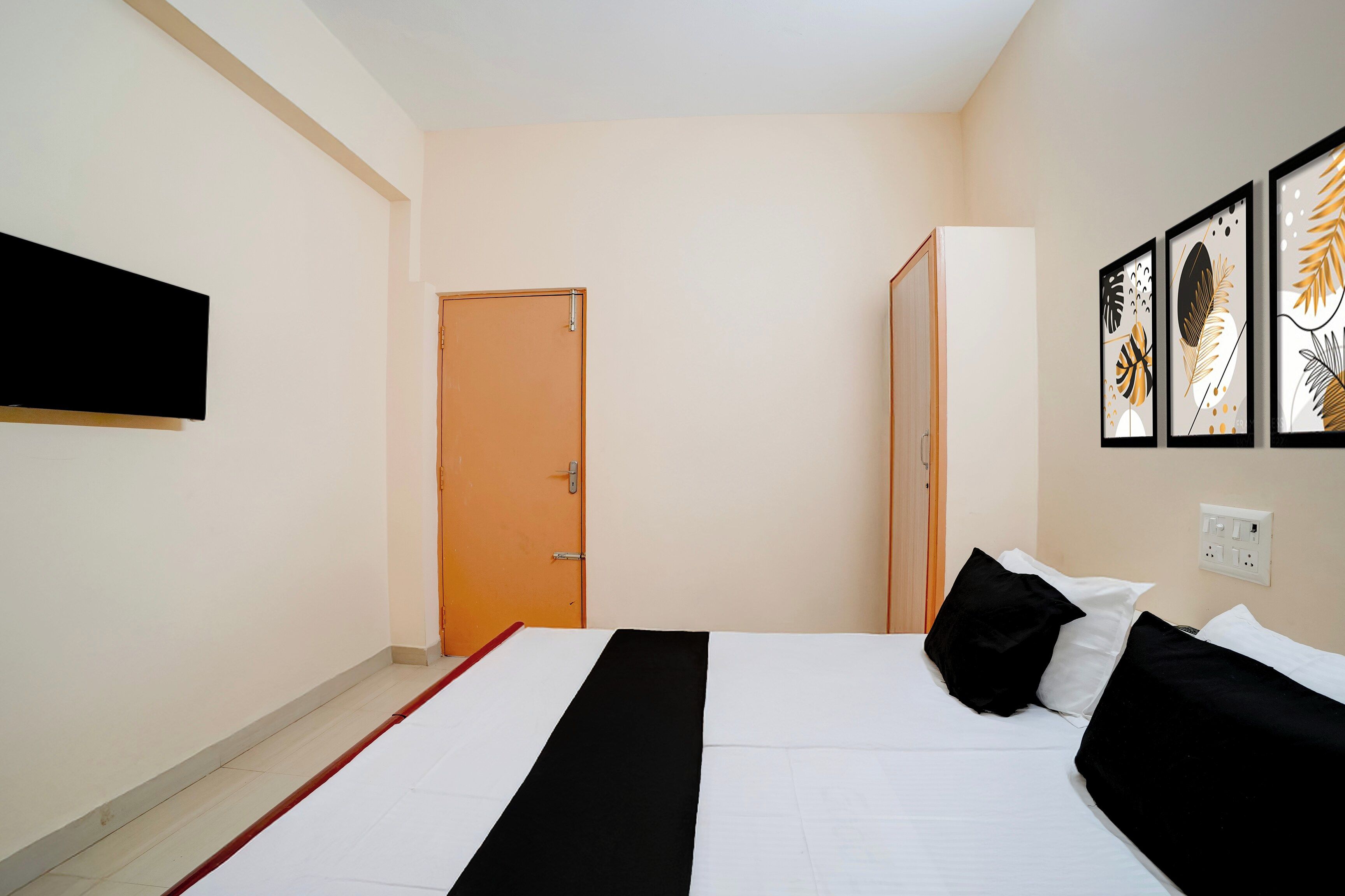A hotel room with a bed, a wardrobe, a door, and a wall-mounted artwork.