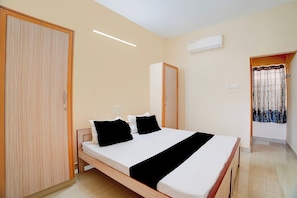 Une chambre à coucher avec un lit, deux oreillers, une armoire et un appareil de climatisation.