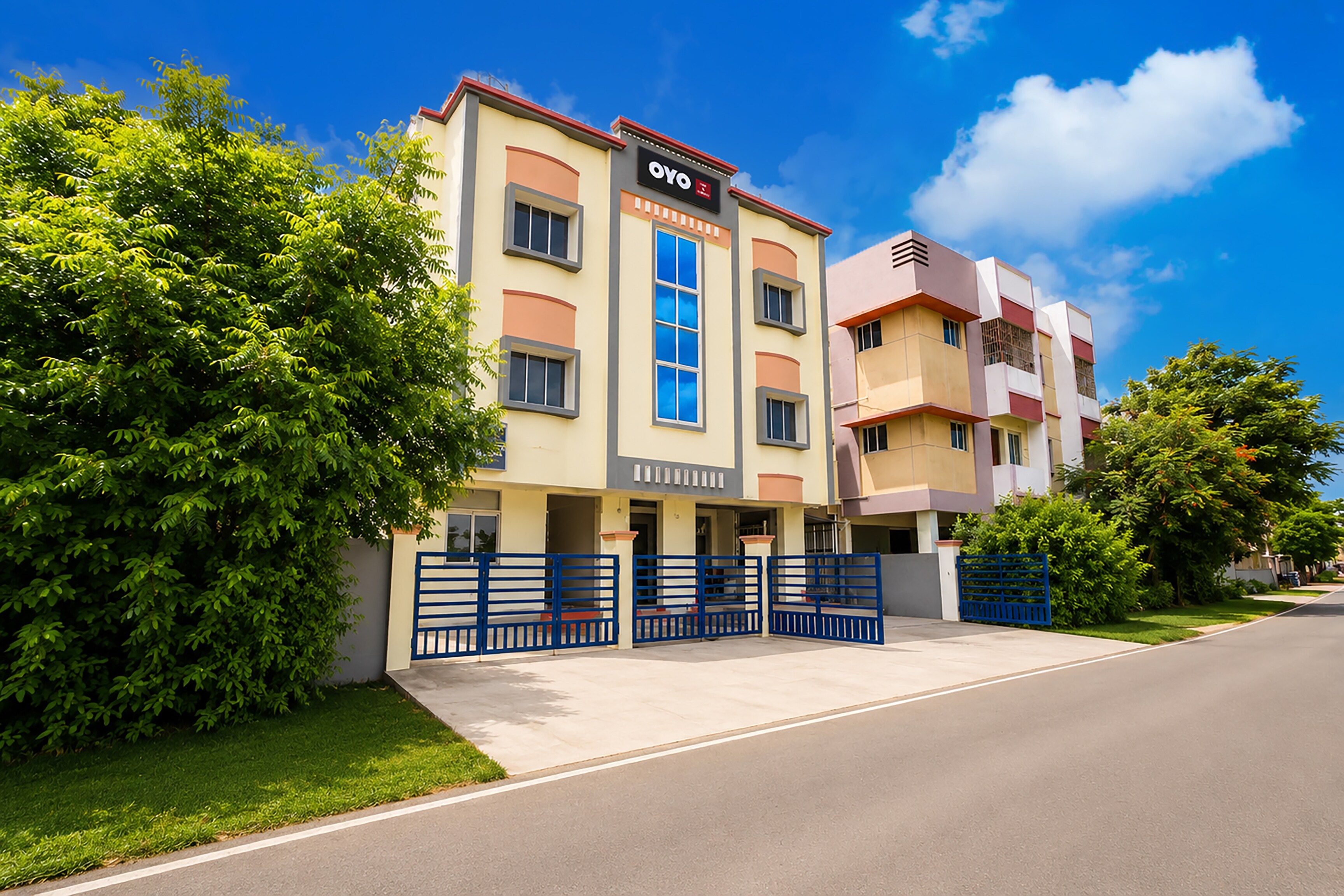 A multi-story hotel with a prominent 'OYO' sign, a gated entrance, and a well-maintained lawn.