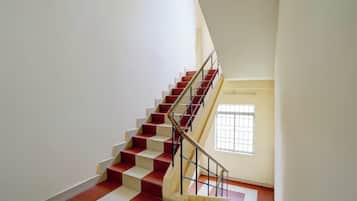 A staircase with red and white steps, a metal handrail, and a window with bars.