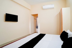 A hotel room with a bed, a flat-screen TV mounted on the wall, and an air conditioning unit above the bed. - Hotel O NL Residency (Chengalpattu)