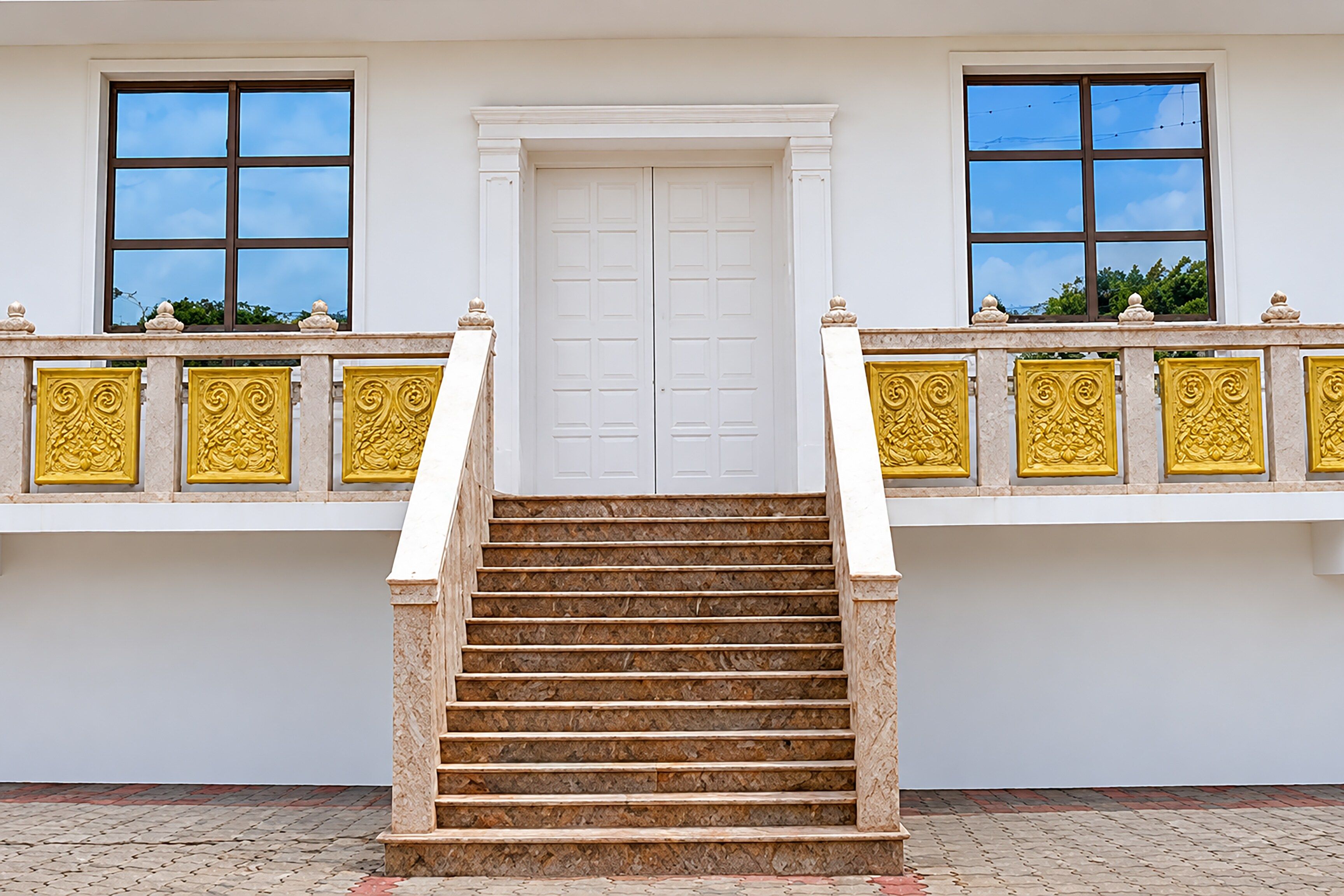 A staircase leading to a white door with a balcony railing featuring decorative golden elements.