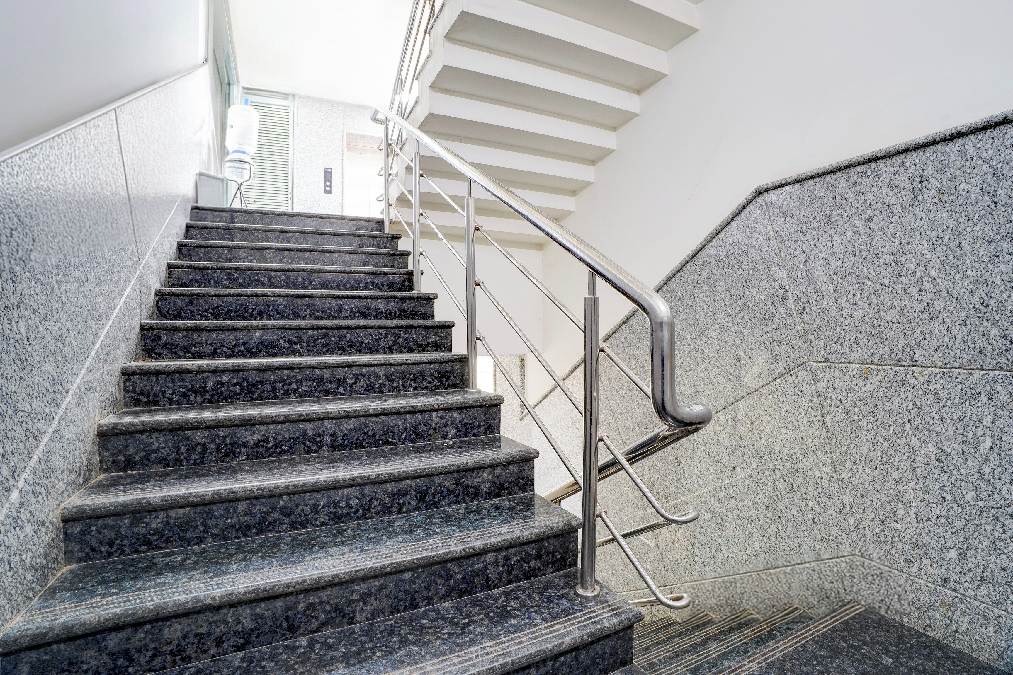 A staircase with a metal handrail and granite steps.